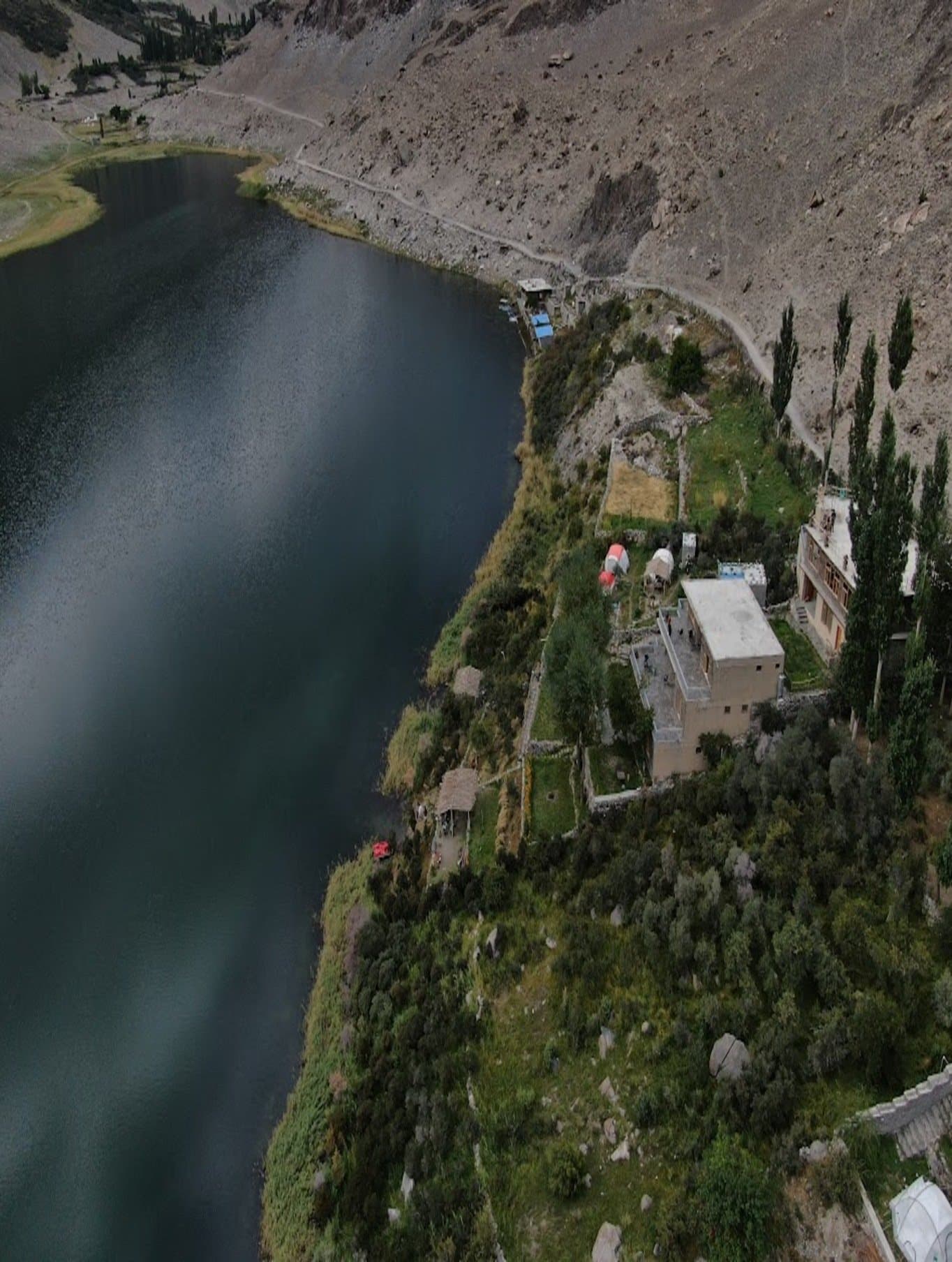 Aerial view of a mountain lake with a lodge and camping structures on its shore
