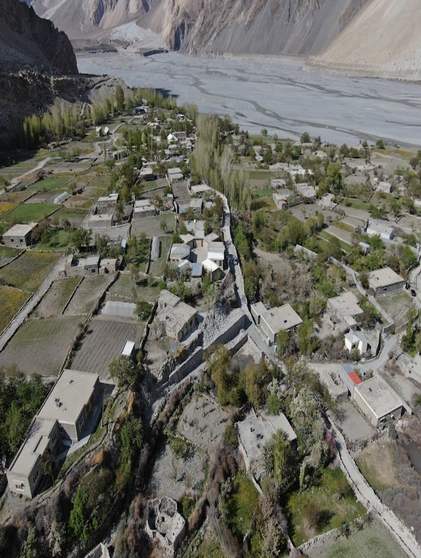 Aerial view of a terraced mountain village along a river in Gilgit-Baltistan