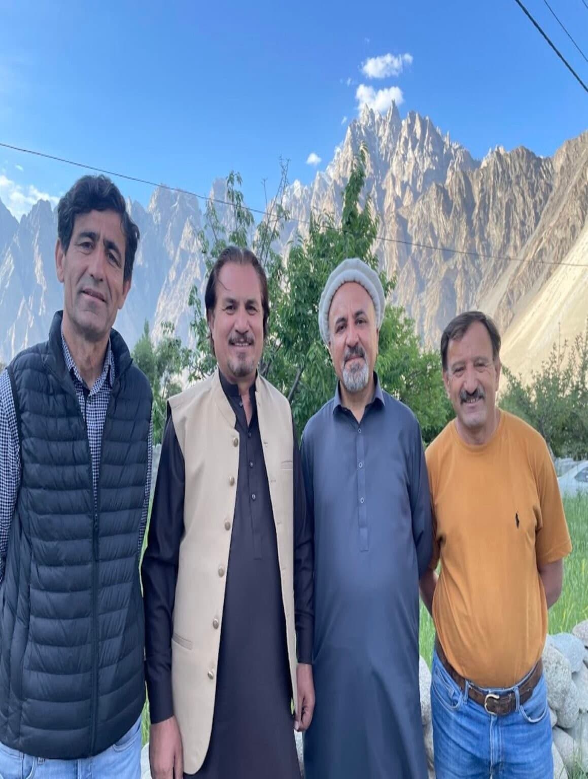 A group of four local men standing together with the Passu Cones behind them