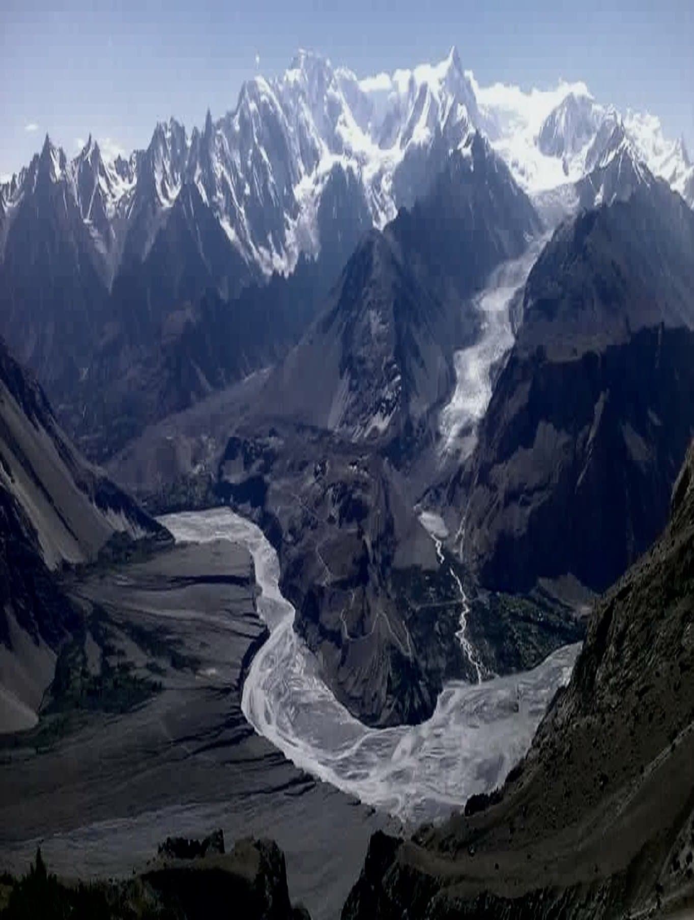 Aerial view of a glacier and braided river valley in Gilgit-Baltistan, framed by snow-capped Karakoram peaks