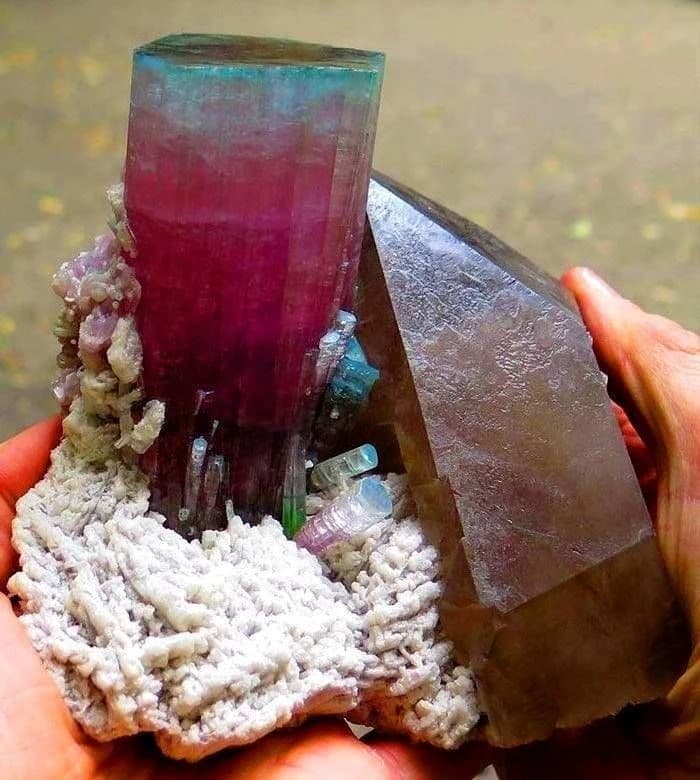 Natural bi-color pink and green tourmaline crystal on matrix, held in hand